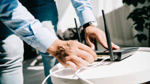 Closeup of a man's hands plugging in a router at a desk