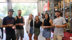 A group of Lakeland Networks staff stand together in a garage bay at a company event.