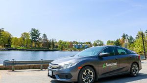 grey car with lakeland logo on the side parked in front of a lake