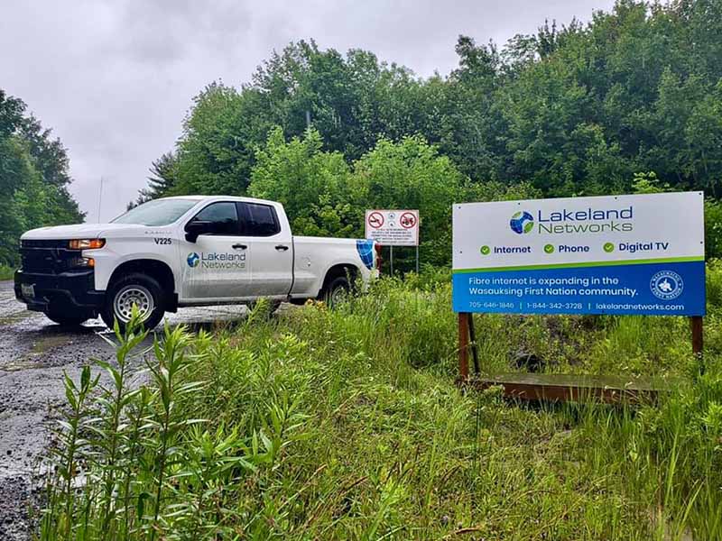 A billboard advertising Lakeland Networks fibre internet in Wasauksing First Nation, with a Lakeland Networks truck in the background