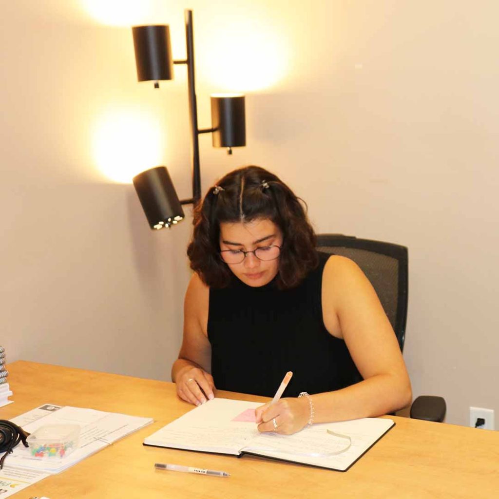 Lakeland Networks' People & Culture Coordinator Chantel Musselman sits at a desk writing in a notebook.