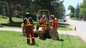 A Lakeland Networks crew of 4 men in orange safety gear works with equipment to install fibre internet in Bracebridge