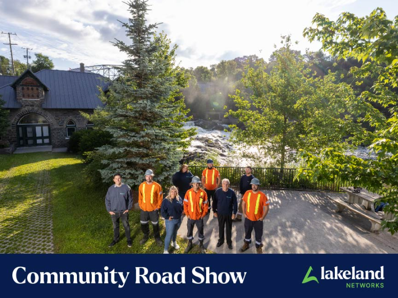 A group shot of Lakeland staff standing in front of trees and a damn with text below reading "Community road show"