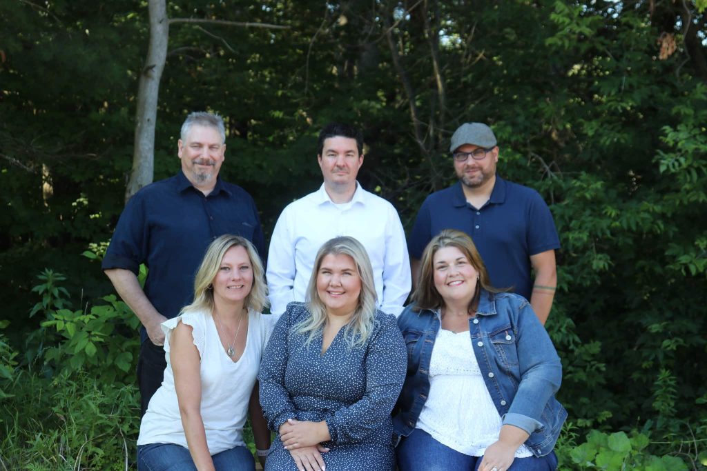 6 member of the Lakeland Service Team smiling at the camera, 3 are standing and 3 sitting in front of them.