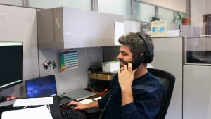 Lakeland staff member holding landline phone to ear in office cubicle and smiling