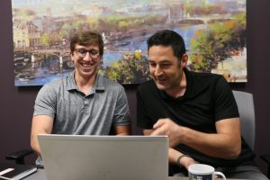 Two men looking and pointing at a laptop screen.