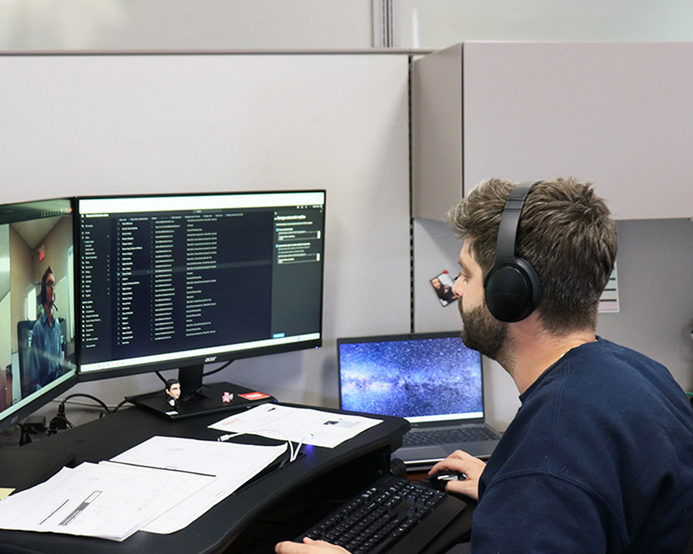 Lakeland staff member wearing a headset, on a virtual call, looking at two monitors.